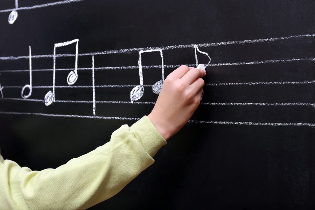 Writing musical notes on blackboard