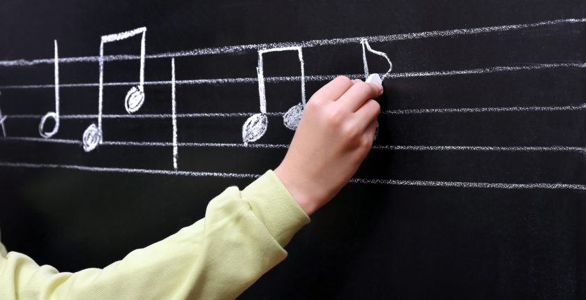 Writing musical notes on blackboard