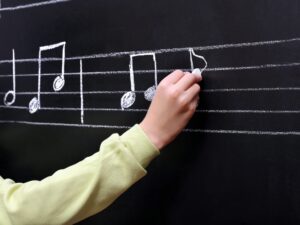 Writing musical notes on blackboard