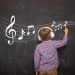 Boy writing musical notes on the blackboard