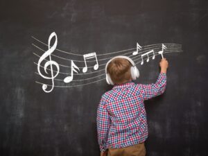 Boy writing musical notes on the blackboard